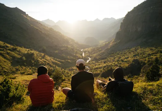 Un groupe d'étudiants en environnement contemple un lever de soleil sur une vallée montagneuse à la GMS